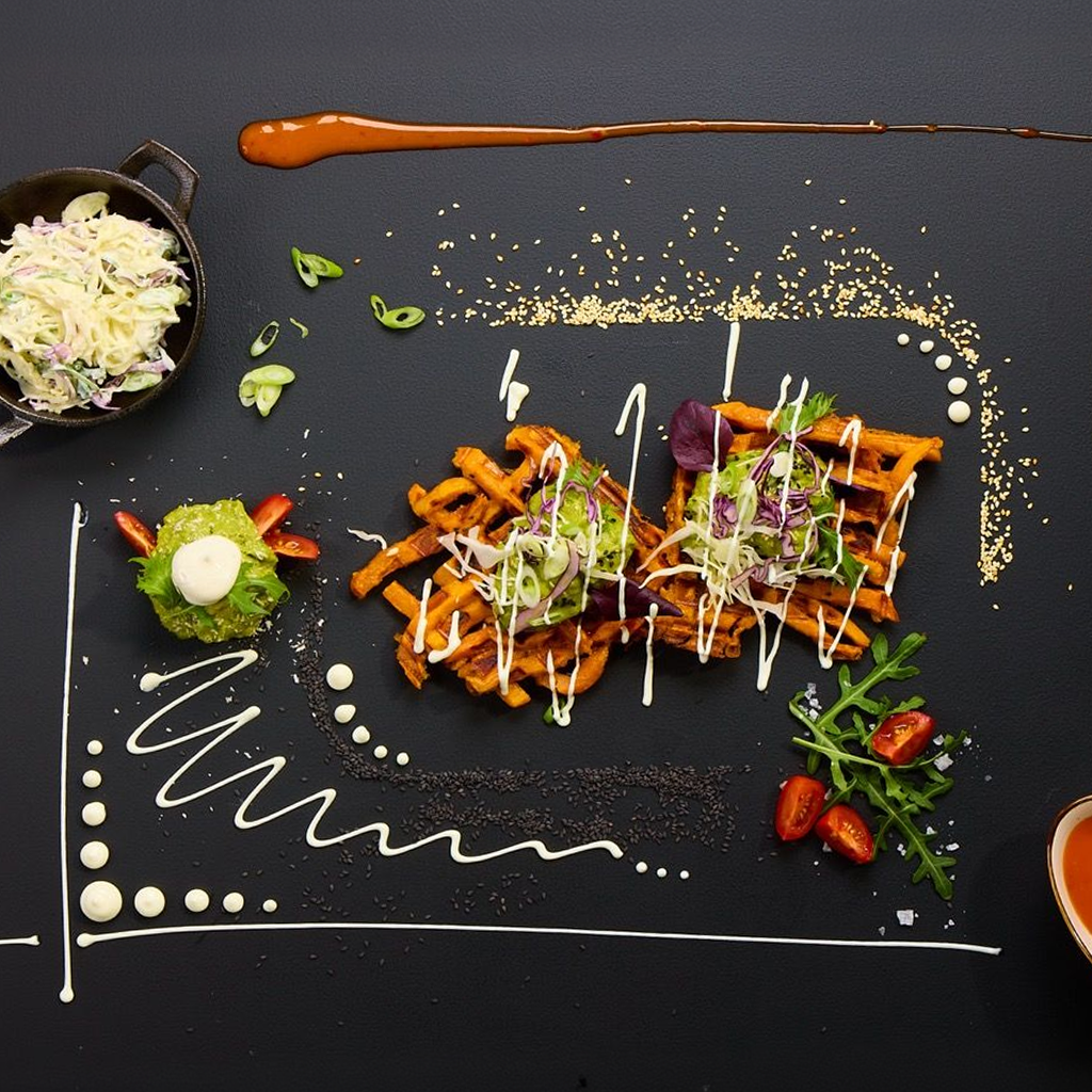 Knusprige Süßkartoffel-Waffel mit Guacamole, Chicken Stripes, Pink Slaw, Rucola, Arizona Ranch Sauce, Sweet & Chili Sauce und Sesam.